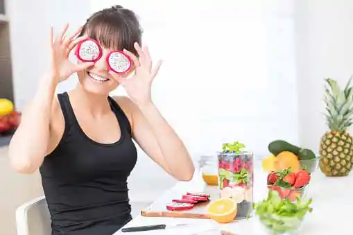 young beautiful woman covering her eyes with slices of dragon fruit